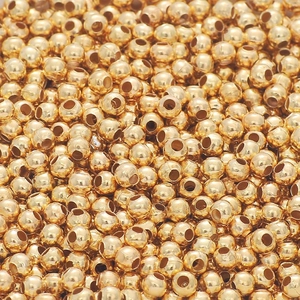 Vista macro di perline distanziatrici tonde dorate lucide per creazioni di gioielli