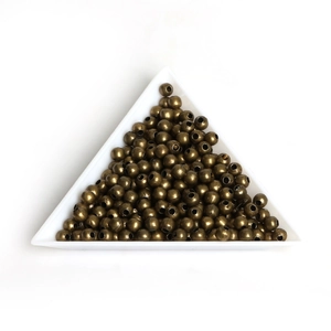 Macro shot of vintage bronze spacer beads for jewelry DIY in a white triangle tray