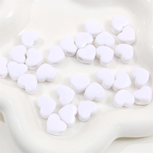 Vue macro de perles de cœur en acrylique blanc sur un plat pour la création de bijoux DIY