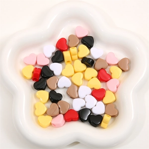 Perles colorées en acrylique en forme de cœur pour bijoux DIY présentées dans un bol blanc