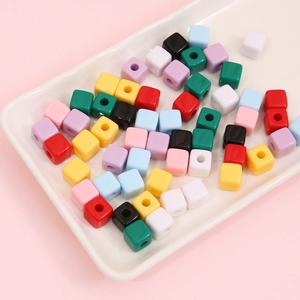 Kleurrijke 10mm acryl vierkante kralen voor DIY sieraden op een wit keramisch bord