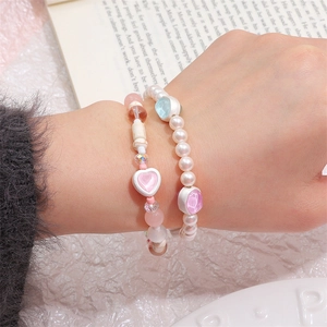 Close-up of handmade charm bracelets with pink heart pendant and colorful gemstone beads