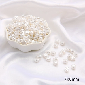 Vue macro de perles d'imitation irrégulières 7x8mm en forme de galet sur satin blanc