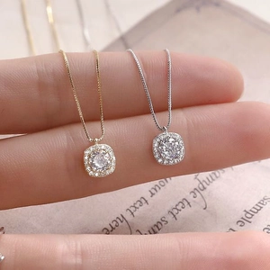 Detail of gold and silver S925 square pendant necklaces held to show scale and sparkle