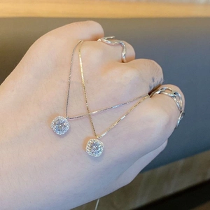 Close-up of square halo pendant necklaces in silver and gold on a hand
