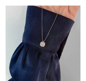 Close-up of a sparkling square halo pendant necklace on a deep blue velvet sleeve