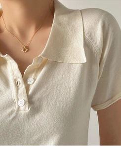 Close-up of golden Mobius twisted ring pendant on a fine chain worn by a model