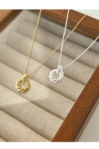 Macro shot of gold and silver twisted Mobius circle necklaces displayed in a wooden case