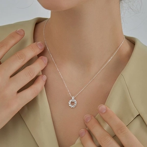 Close-up of 925 sterling silver twisted Mobius ring necklace on model neckline