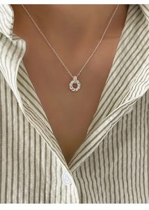Detail of twisted Mobius sterling silver pendant necklace on a woman striped shirt