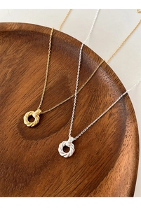 Detailed view of twisted mobius circle pendants in gold and silver finish on wooden tray