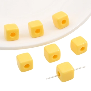 Close-up of bright yellow acrylic cube beads with straight holes for DIY jewelry making
