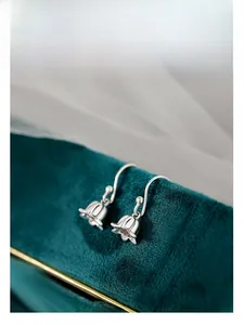 Détail macro de boucles d'oreilles muguet en argent S925 sur velours vert