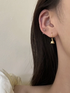 Gros plan d'élégantes boucles d'oreilles muguet dorées portées par un mannequin sous la lumière