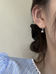 Gros plan de boucles d'oreilles muguet en argent S925 portées par un mannequin femme