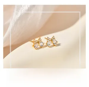 Détail de boucles d'oreilles nœud dorées serties de zircons sur fond de soie douce