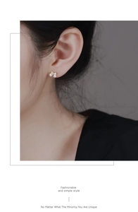 Gros plan de boucles d'oreilles dorées avec deux zircons gouttes portées par le modèle