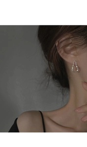 Détail d'une boucle d'oreille pendante en argent S925 portée par un mannequin