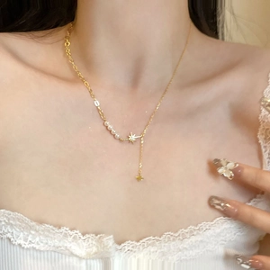 Dettaglio macro del ciondolo a stella dorata con perle e catena elegante a forma di Y