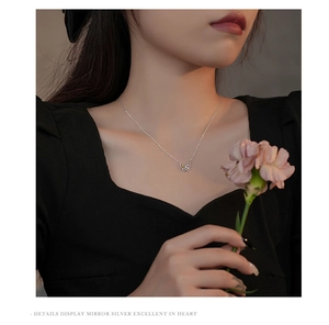 Détail d'un pendentif papillon en argent sur une chaîne délicate portée par un mannequin