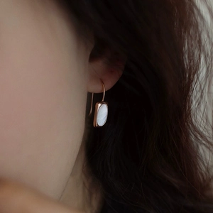 Close-up of rose gold S925 silver earrings with rectangular shell inlay on model