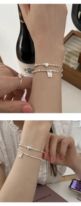 Detail of silver heart charm bracelet and bamboo link chain with engraved square tag