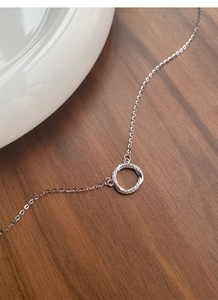 Gros plan du collier Mobius en argent S999 avec pendentif en zircons sur fond de bois