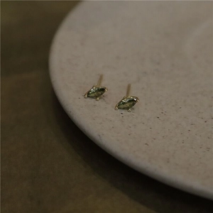Detail of olive green marquise stud earrings on a grey ceramic tray with vintage gold finish