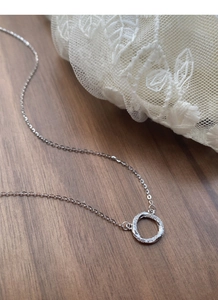 Détail du collier Mobius en argent S999 avec pierres scintillantes sur fond en bois