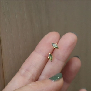 Detail showing olive green marquise stud earring with gold setting held by hand
