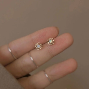 Macro detail of S925 silver gold-plated hollow flower earrings with opal stone inlay
