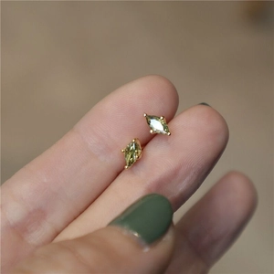 Close-up of marquise-cut green zircon earrings on fingertip with gold plating