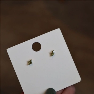 Macro shot of marquise-cut olive green stud earrings in a four-prong gold setting