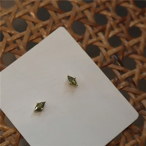 Detail view of marquise-cut green gemstone stud earrings in gold-plated four-prong setting