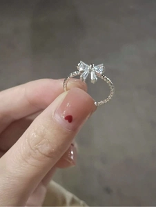 Detail of S925 sterling silver bow ring featuring sparkling zircon and wavy band texture