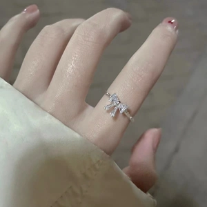 Close-up of S925 sterling silver bow ring with sparkling zircon stones on finger