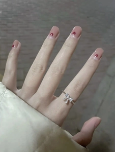 Close-up of a S925 silver bow ring with zircon stones on a model's hand with nail art