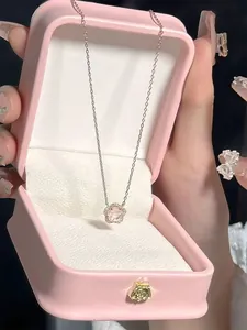 Gros plan du pendentif fleur de cerisier doré rose avec cristal rose en boîte