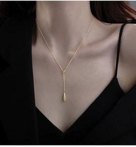 Gros plan d'un collier en Y minimaliste doré avec un pendentif en forme de goutte d'eau