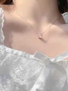 Gros plan du collier pendentif fleur de cerisier rose sur modèle en robe dentelle