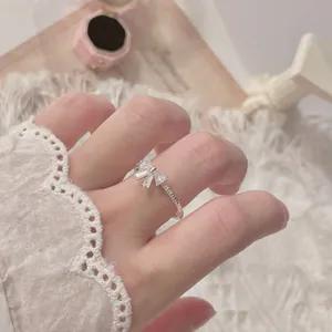 Detail of S925 sterling silver bow ring with zircons on model's finger with lace