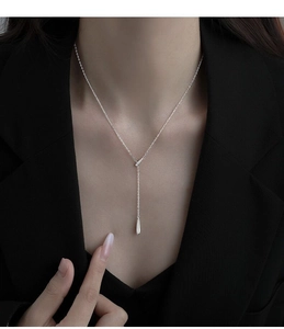 Détail du collier en Y argenté avec pendentif goutte poli porté par un mannequin chic