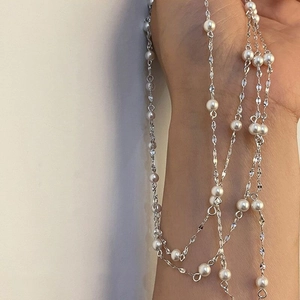 Detail of multi-layered silver necklace featuring white pearls and delicate chains