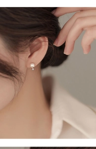 Close-up of elegant S925 sterling silver drop earring with round white pearl on model ear