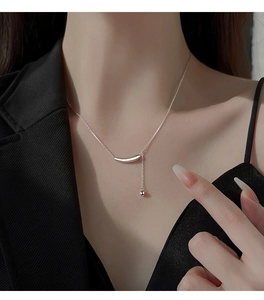 Gros plan détaillé d'un collier en Y argenté avec pendentif aubergine sur un blazer