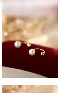 Detailed close-up of S925 silver pearl earrings with gold beads on red velvet display