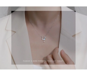Detalle del collar S925 plata con luna y piedra azul en una mujer con chaqueta blanca