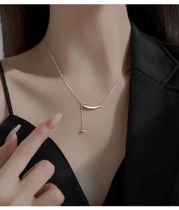 Gros plan d'un collier en argent S925 avec pendentif arc et long gland sur un mannequin