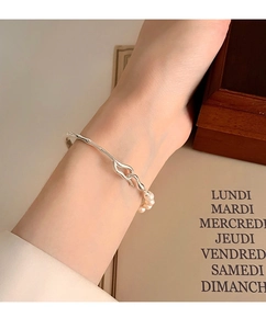 Gros plan d'un bracelet manchette en argent S925 aux formes fluides et trois perles d'eau douce
