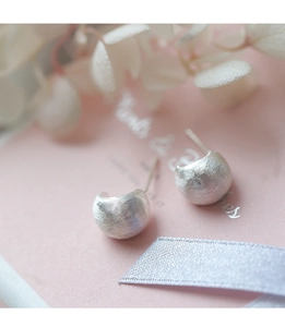 Vue macro des boucles d'oreilles courbes en argent S925 avec finition brossée mate
